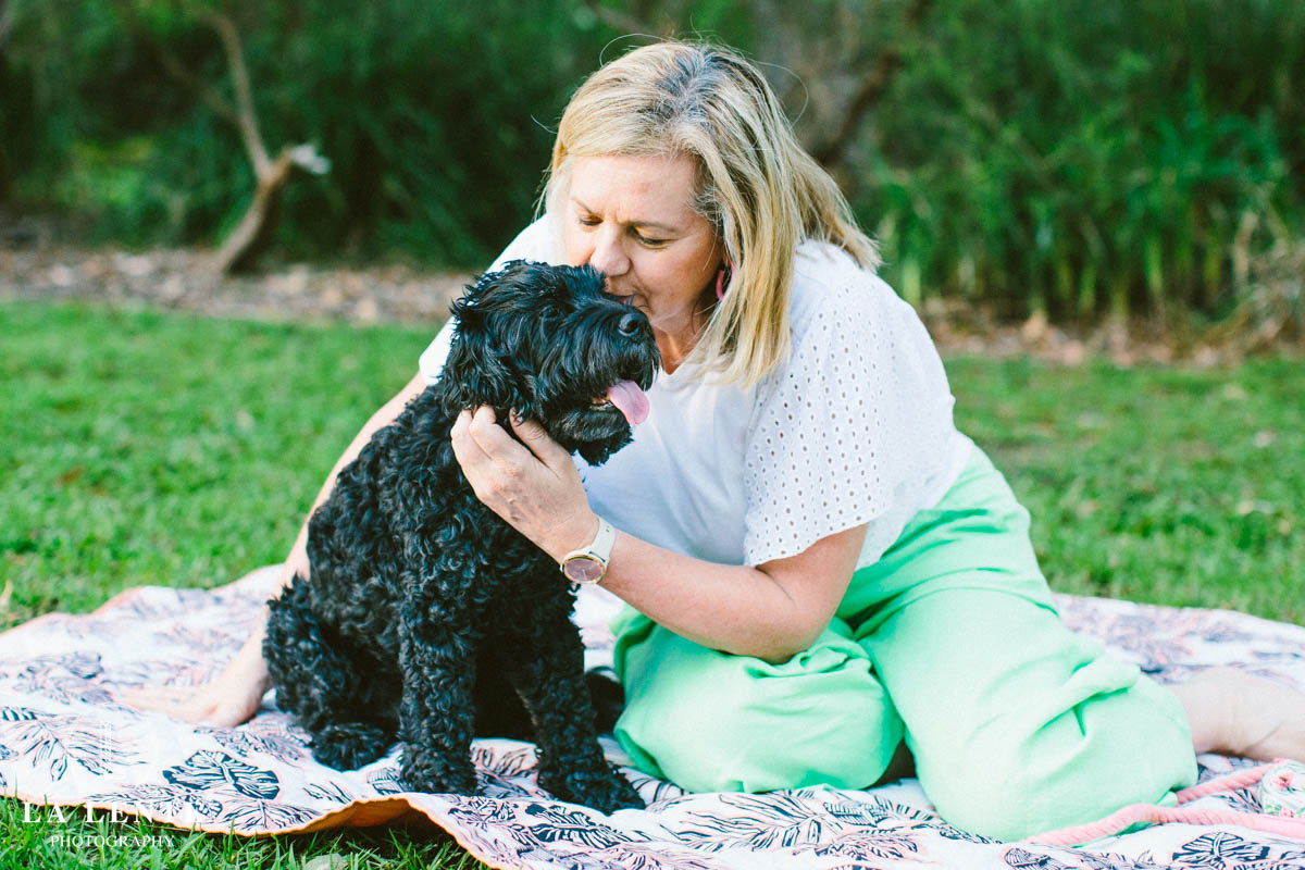 Black Cavoodle hugged by woman in park
